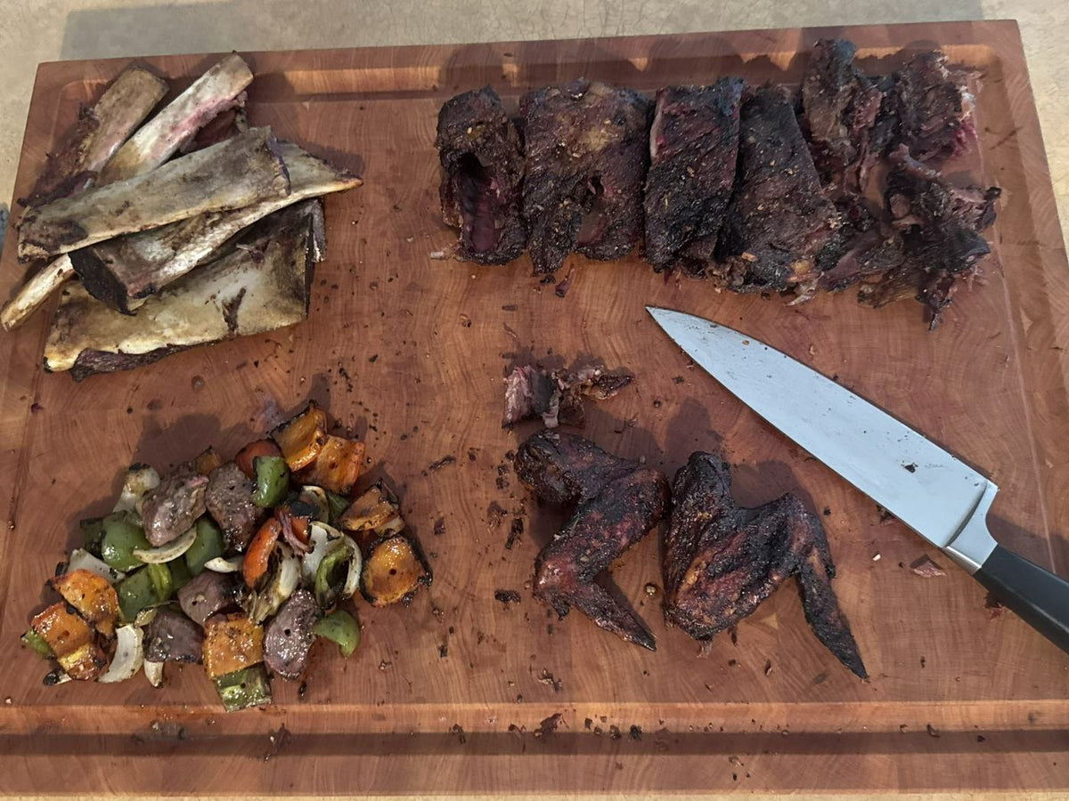 Cherry end grain cutting board with smoked ribs, wings and vegetables in a home kitchen
