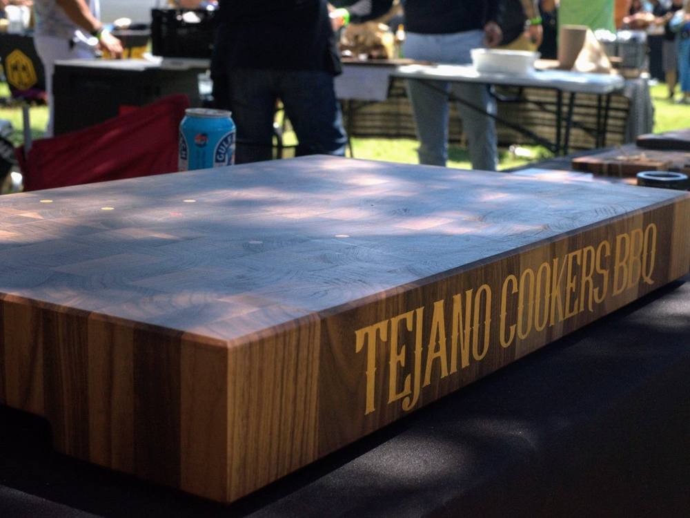 Tejano Cookers BBQ walnut end grain butcher block with the team name inlaid in contrasting hardwood along the side, at a cookoff